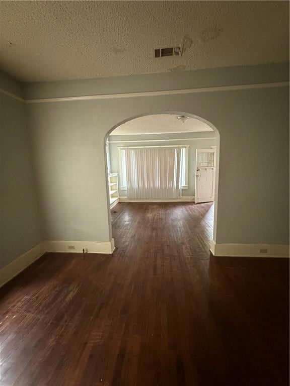 Empty room featuring arched walkways, dark wood-ty