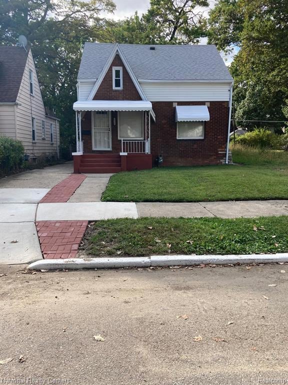 Bungalow-style home with covered porch, a front yard, brick siding, and a shingled roof