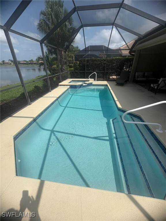 View of pool featuring a sunroom, a patio, a pool with connected hot tub, and a lanai