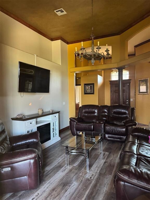 Living area featuring a chandelier, crown molding, and wood finished floors