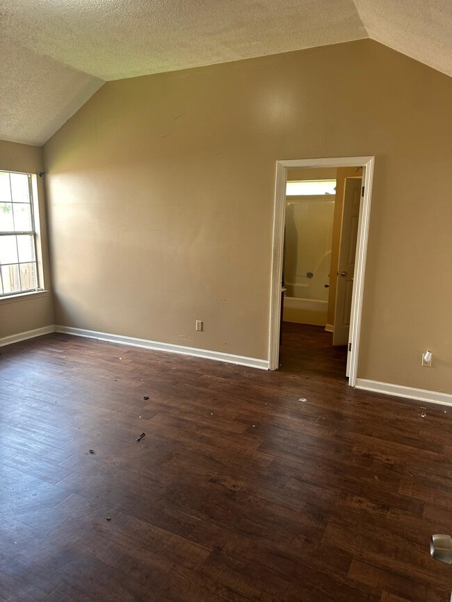 Empty room with a textured ceiling, lofted ceiling