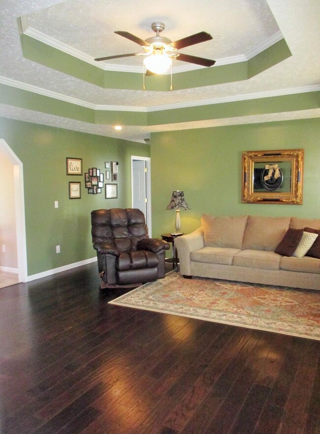 Living room has hardwood, double trey ceiling, recessed and ceiling fan lighting