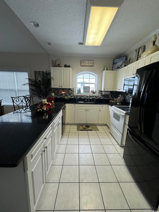 Kitchen with black appliances, decorative backspla