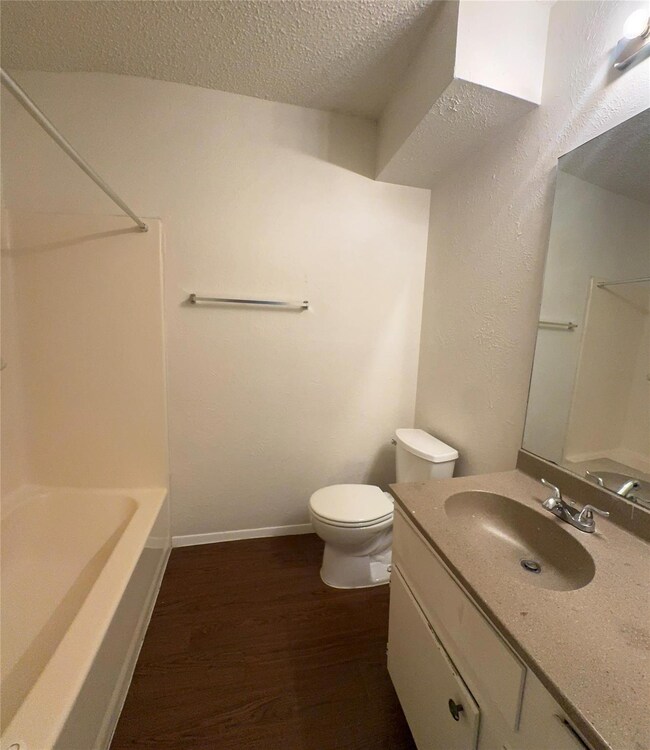 Full bath featuring wood finished floors, toilet,