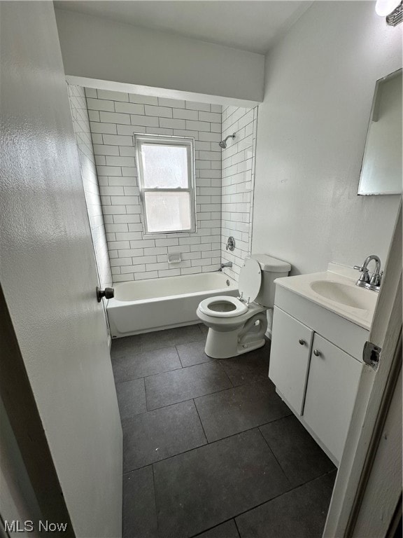 Full bathroom with tile floors, toilet, vanity, and tiled shower / bath