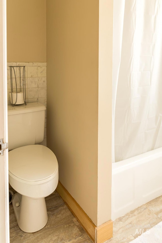 Bathroom with tile walls and shower / bath combo with shower curtain