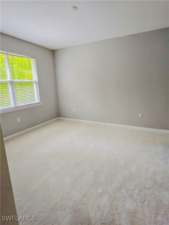 Carpeted empty room featuring baseboards