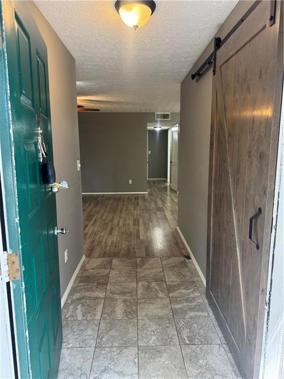 Hall featuring a barn door and a textured ceiling