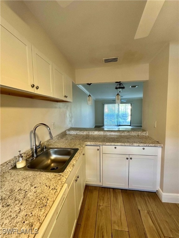 Kitchen featuring white cabinetry, light wood-style flooring, light stone counters, hanging light fixtures, and crown molding