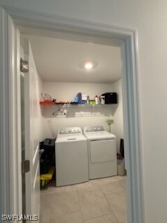 Laundry room featuring light tile patterned floors and washing machine and clothes dryer