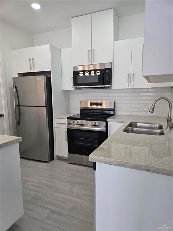 Kitchen featuring white cabinets, a sink, stainless steel electric range, tasteful backsplash, and fridge
