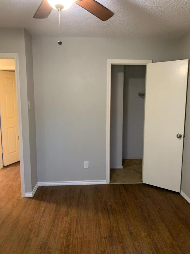 Unfurnished bedroom with a textured ceiling, ceiling fan, dark hardwood / wood-style flooring, and a closet