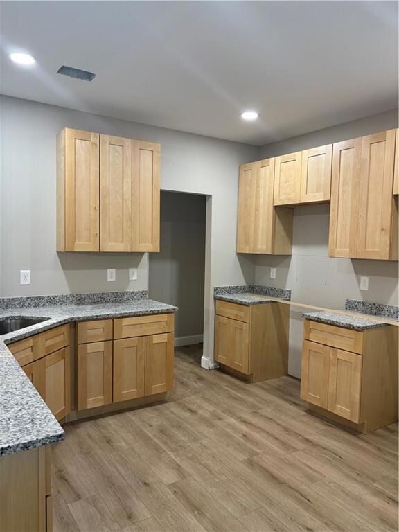 Kitchen featuring light wood-type flooring, light brown cabinets, recessed lighting, and light stone countertops