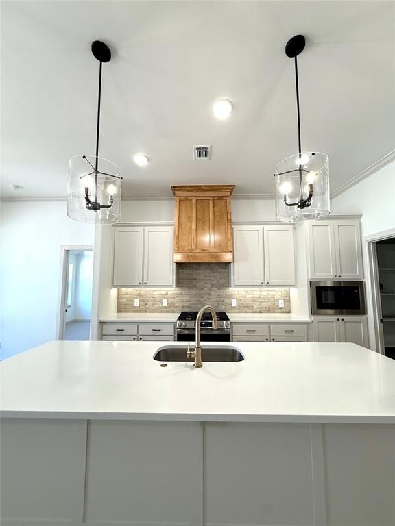 Kitchen with a chandelier, a sink, decorative backsplash, ornamental molding, and light countertops