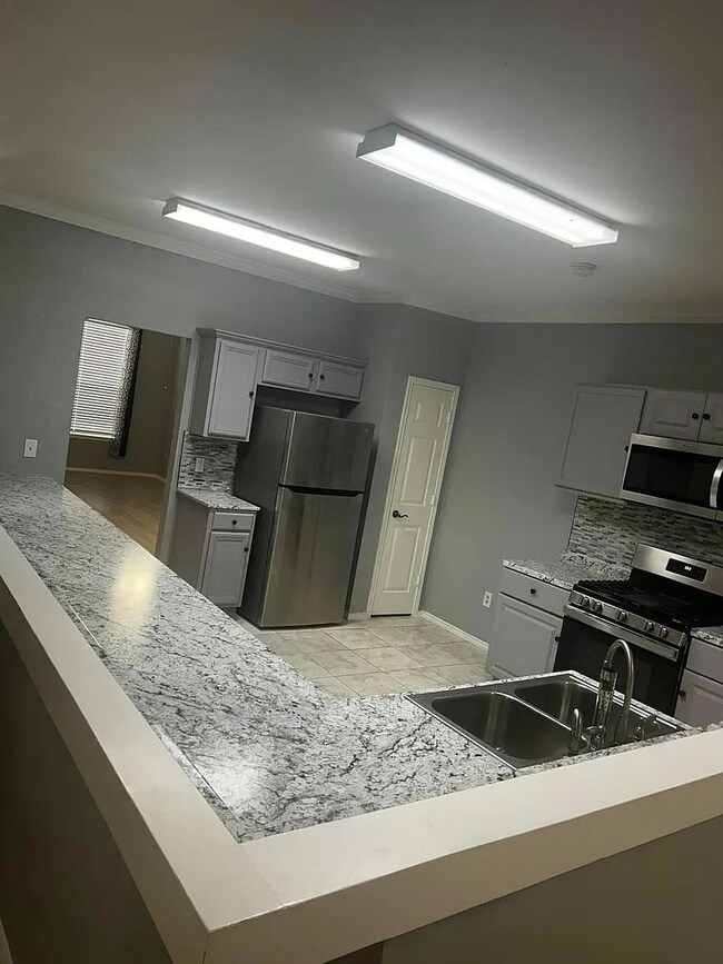 Kitchen with gray cabinetry, appliances with stain