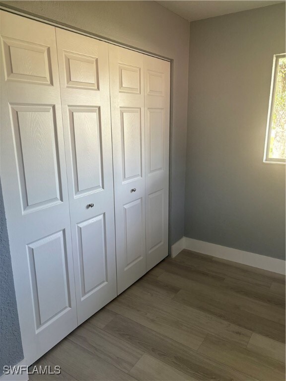 Unfurnished bedroom with wood finished floors, a c