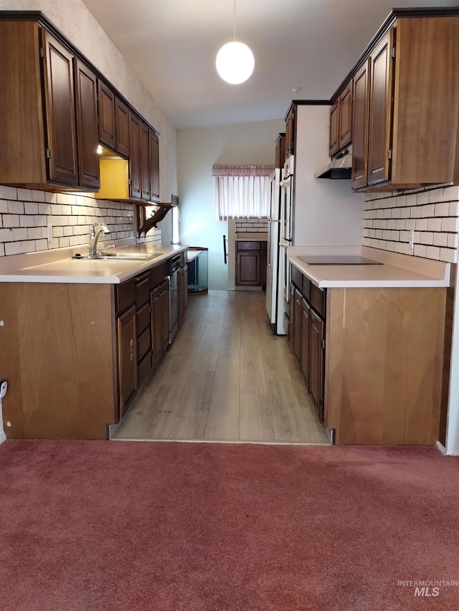 Kitchen featuring decorative backsplash, light countertops, hanging light fixtures, and light carpet