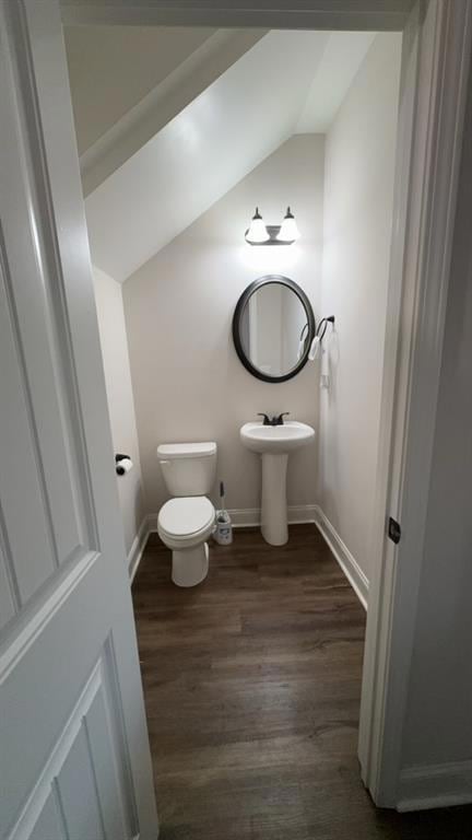 Half bath with lofted ceiling and wood finished floors