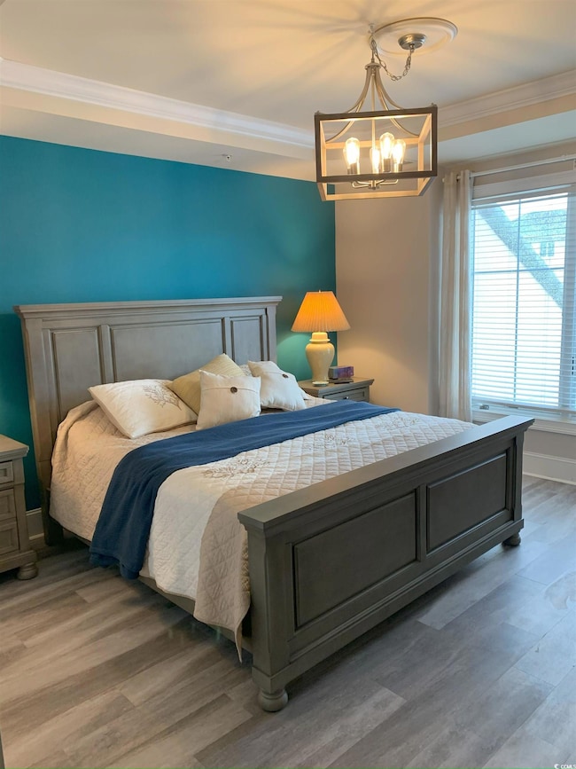 Bedroom featuring crown molding, a chandelier, and hardwood / wood-style flooring