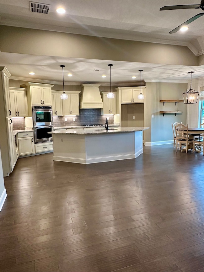 Kitchen with premium range hood, ornamental molding, stainless steel double oven, backsplash, and a ceiling fan