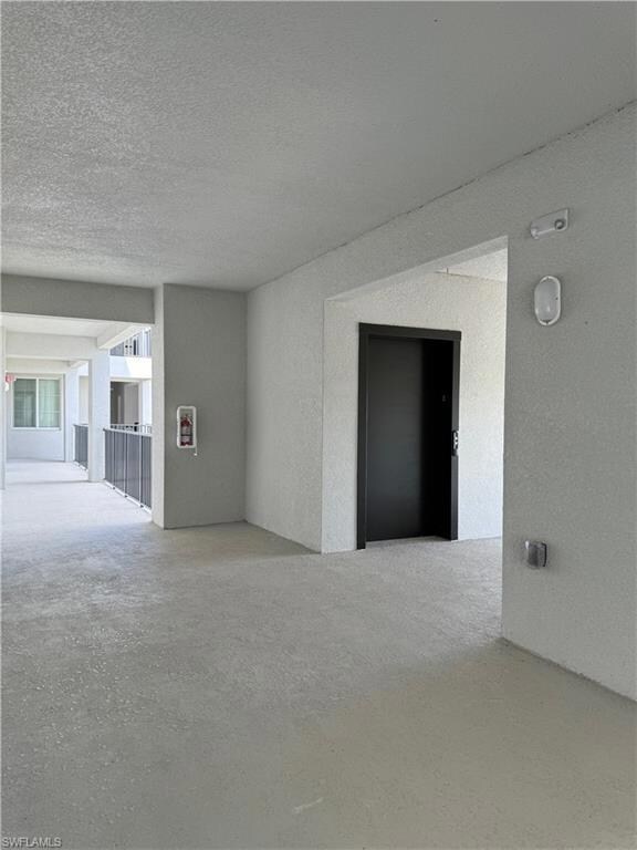 Empty room featuring a textured ceiling and elevat