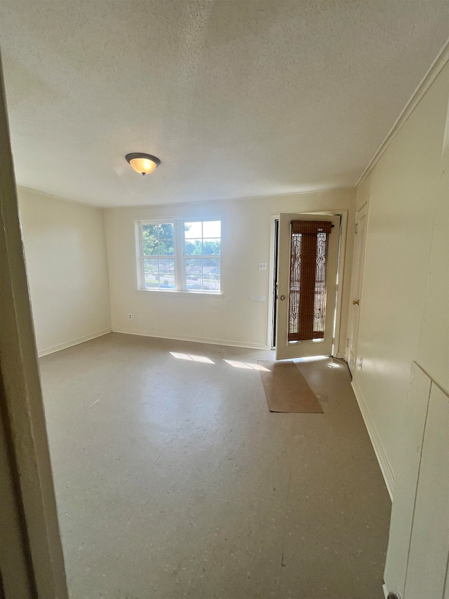 Spare room featuring a textured ceiling and baseboards