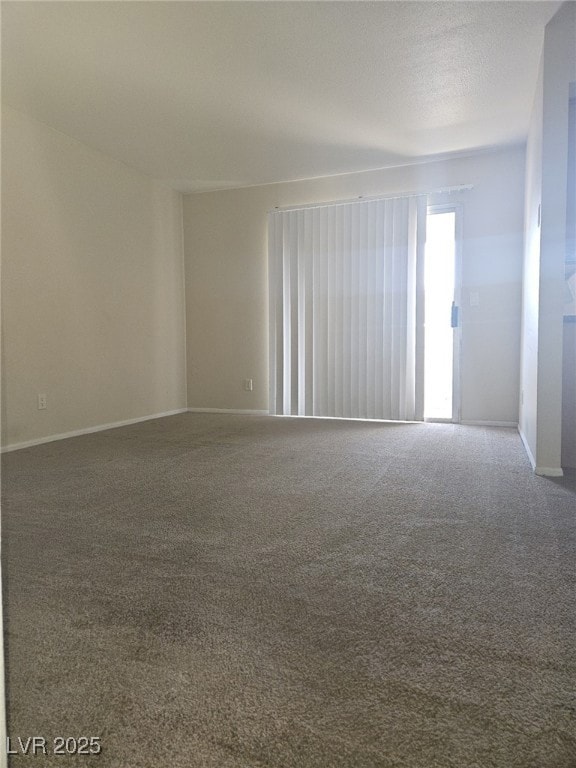 Carpeted spare room featuring baseboards