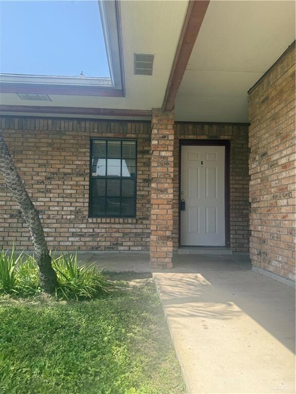 Doorway to property with brick siding and covered porch