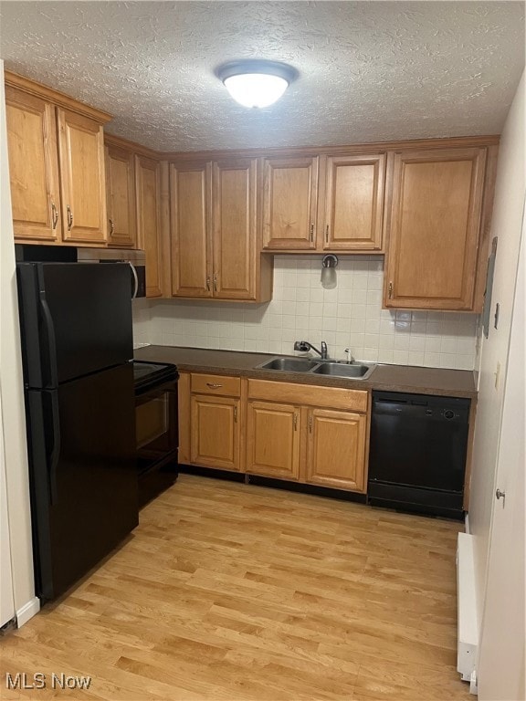 Kitchen with dark countertops, fridge, tasteful backsplash, light wood-type flooring, and dishwasher