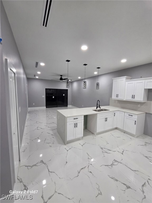 Kitchen with white cabinets, recessed lighting, a peninsula, open floor plan, and decorative light fixtures