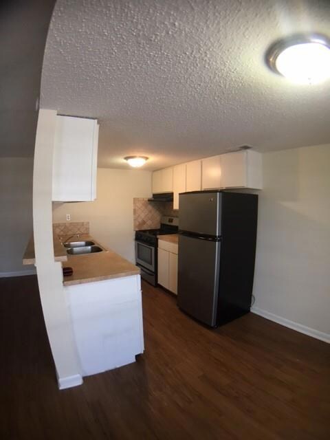 Kitchen featuring a sink, white cabinetry, a text