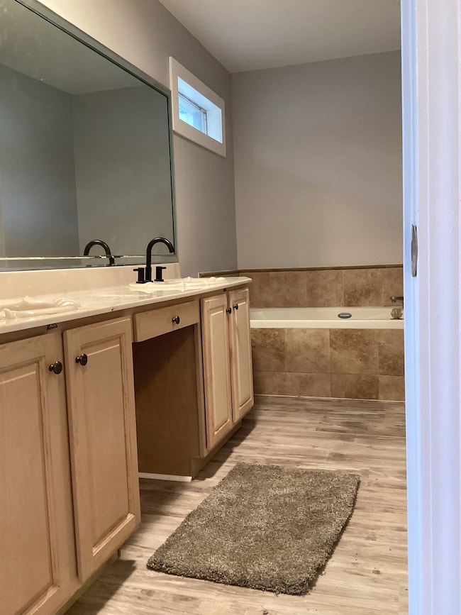 Full bathroom with wood finished floors, a bath, and vanity