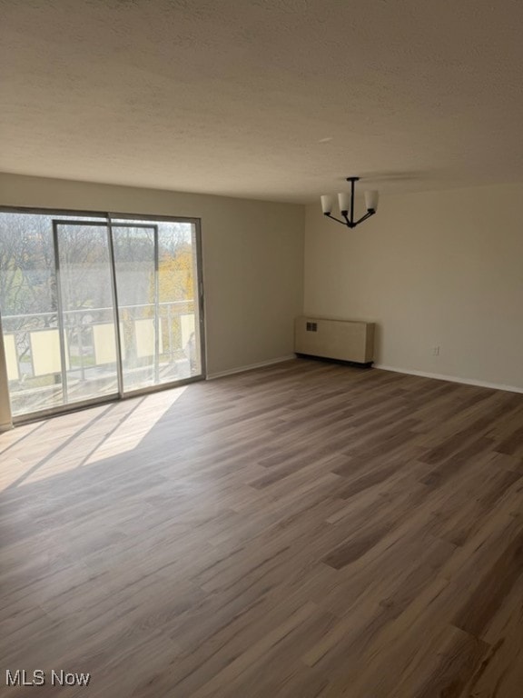 Spare room with wood finished floors, a textured ceiling, and a chandelier