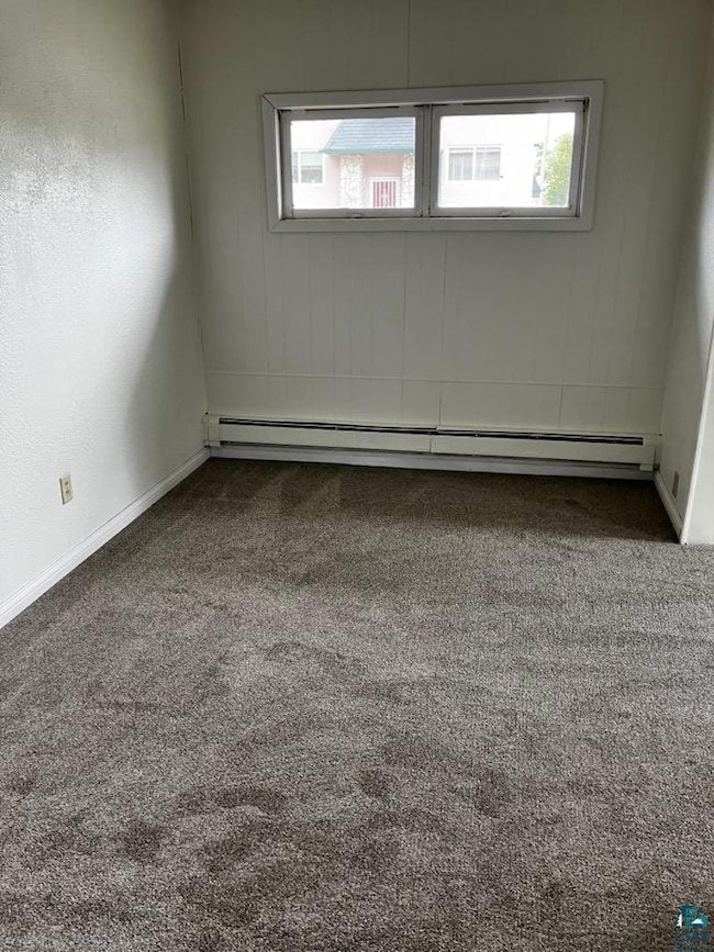 Spare room with carpet flooring and a baseboard heating unit