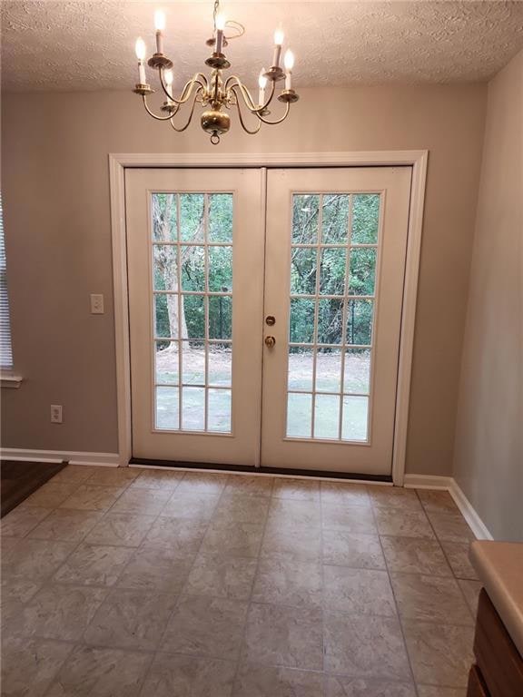 Doorway with french doors, a textured ceiling, and a chandelier