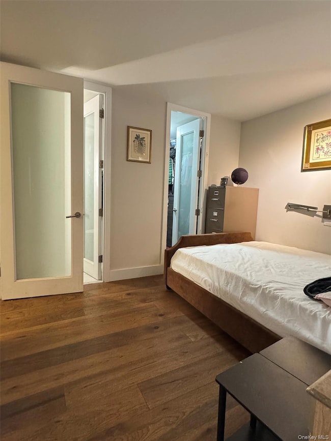 Bedroom with dark wood finished floors and baseboards