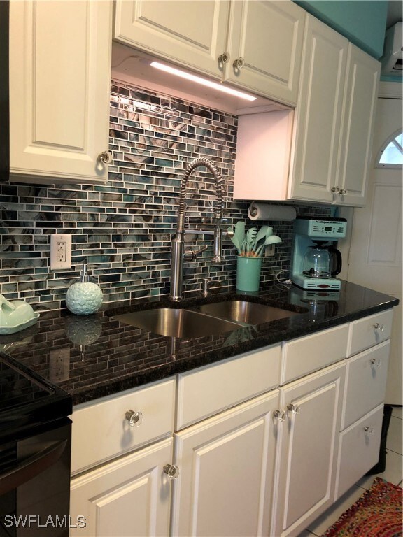 Kitchen with tasteful backsplash, white cabinets,