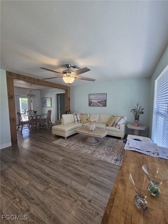 Living area with dark wood finished floors, a textured ceiling, and a ceiling fan