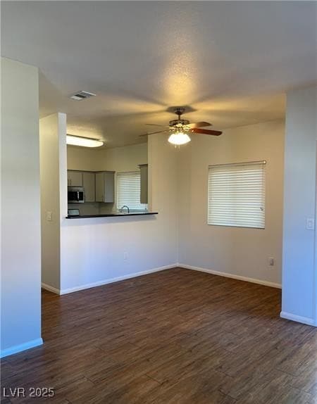 Unfurnished living room with dark wood-type flooring and a ceiling fan
