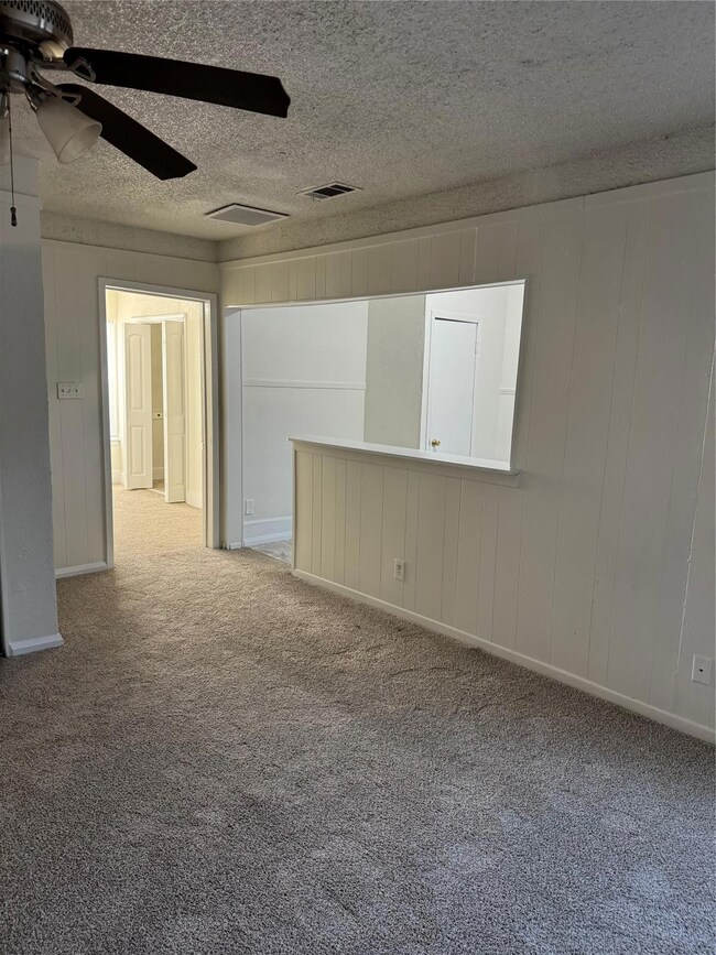 Empty room with carpet flooring, a textured ceilin