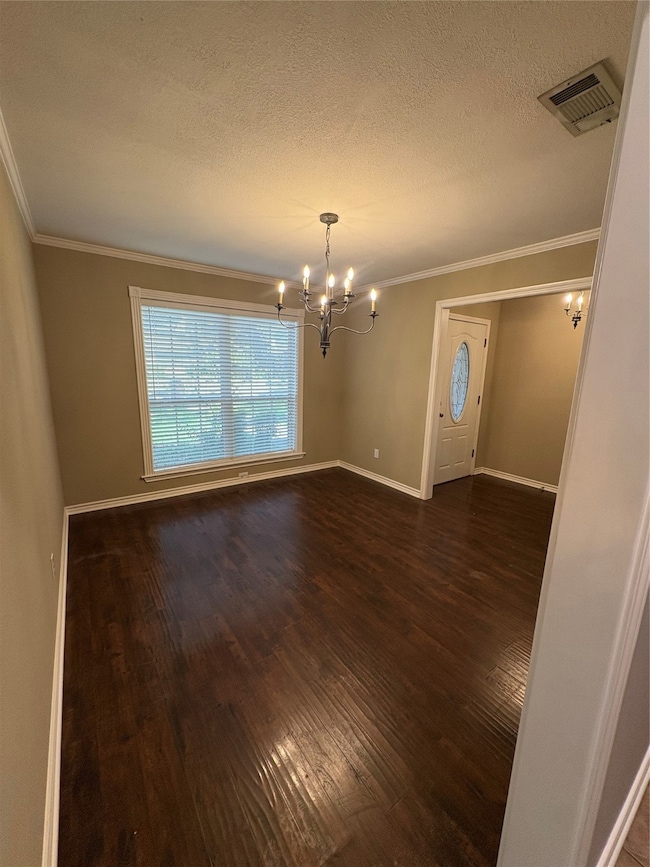 Dining room with crown molding, a chandelier, a textured ceiling, and dark wood-style flooring