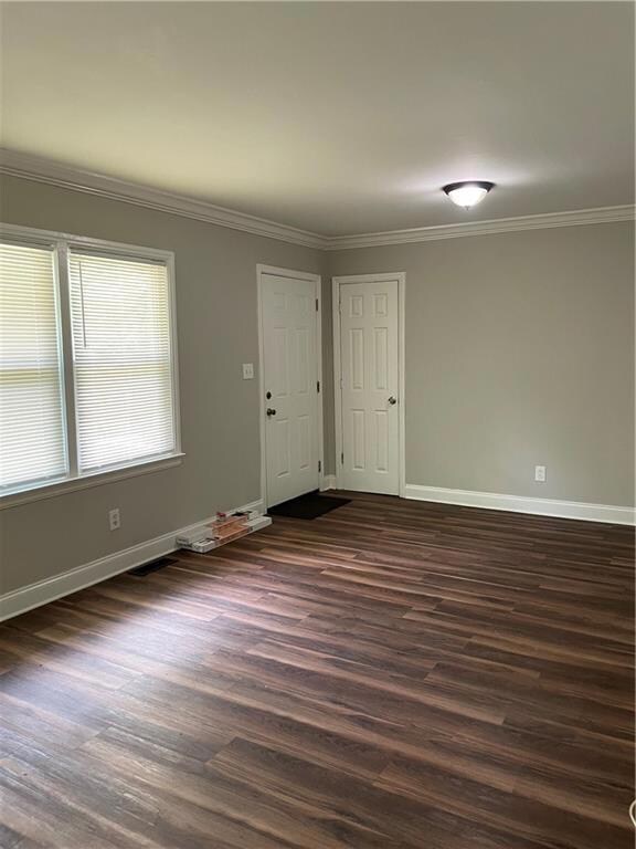 Combination living room/dining room with crown molding, ceiling fan, and dark wood-type flooring