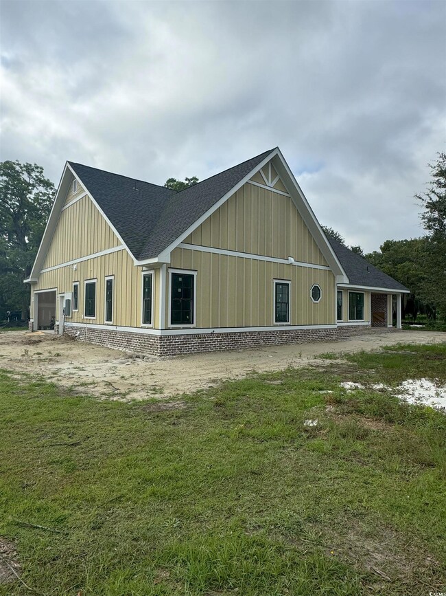View of front facade with board and batten siding, a shingled roof, and a front yard