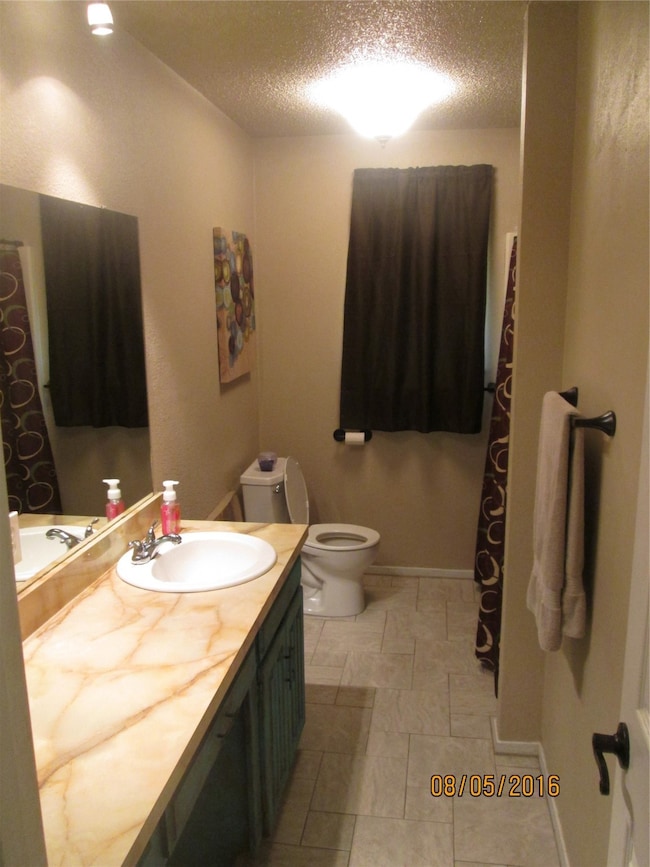 Full bath with a textured ceiling, vanity, and a shower with shower curtain