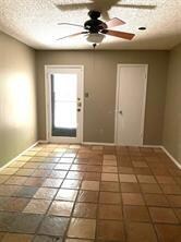 Doorway with a ceiling fan and a textured ceiling
