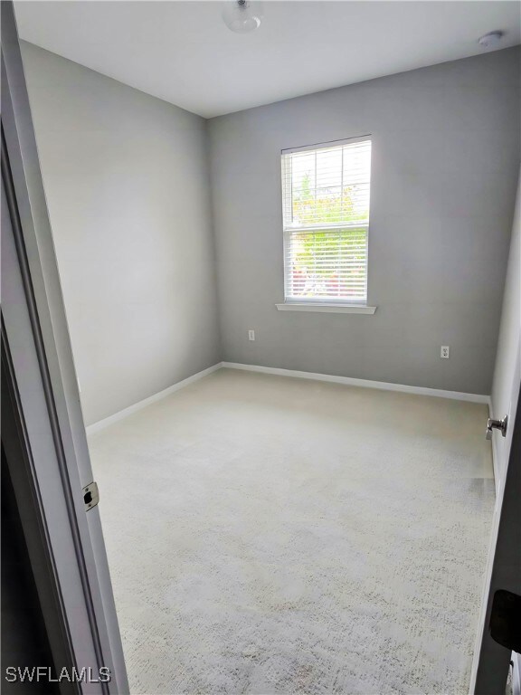 Carpeted spare room with baseboards and a smoke de