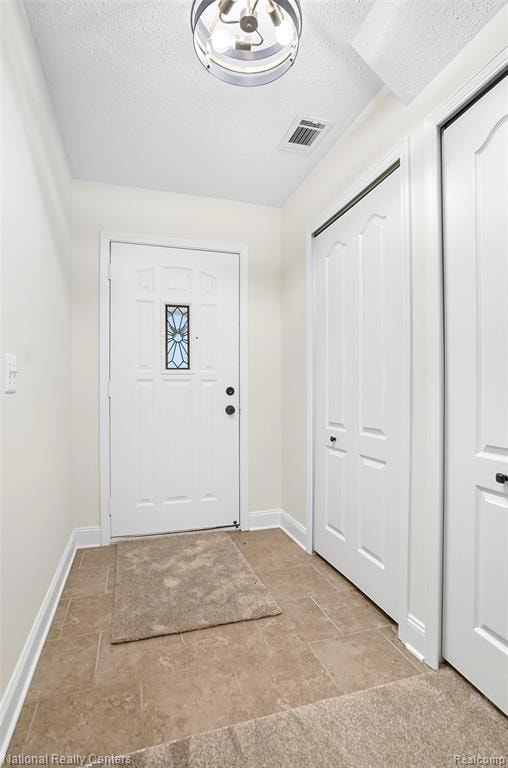 Entryway with a textured ceiling and stone tile floors