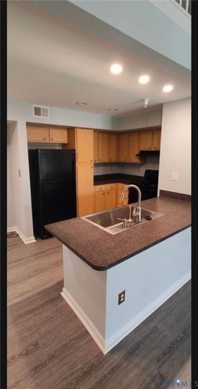 Kitchen with dark countertops, black appliances, dark wood-style floors, a peninsula, and recessed lighting