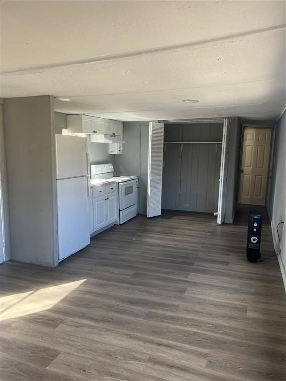 Kitchen with refrigerator, white cabinetry, light countertops, range, and dark wood finished floors