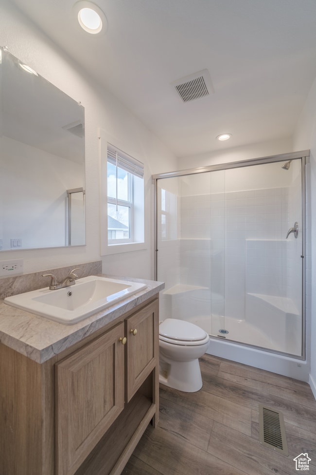 Full bath with vanity, toilet, visible vents, and a stall shower